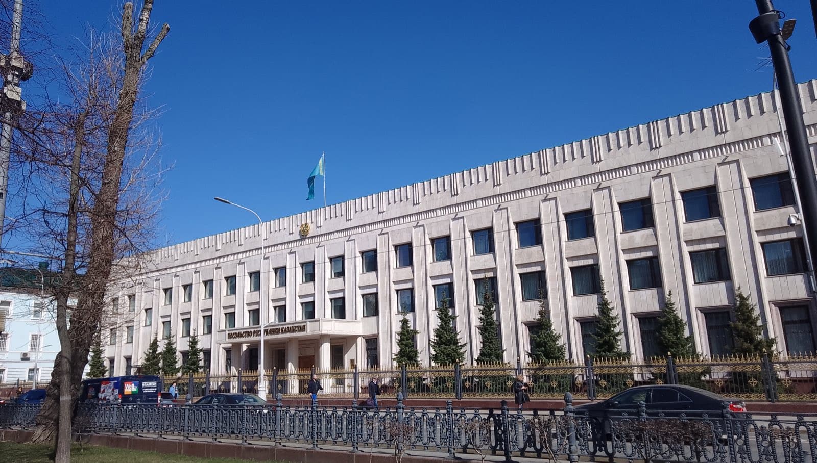 Посольство Казахстана в Москве на Чистопрудном бульваре: светлое здание с колоннами и флагом, вдоль ограды припаркованы машины